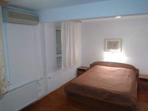 Simple, functional bedroom with a single bed, bedside table, and framed picture.