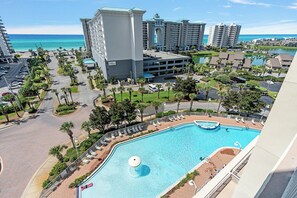 A resort with a swimming pool, palm trees, and a view of the ocean.