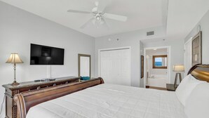 Ein Hotelzimmer mit einem Bett, einem Fernseher, einem Schreibtisch, einem Spiegel und einer Tür zu einem Badezimmer.