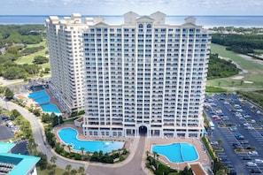 Un hôtel de grande hauteur doté de nombreux balcons, d’un atrium central et de deux piscines.