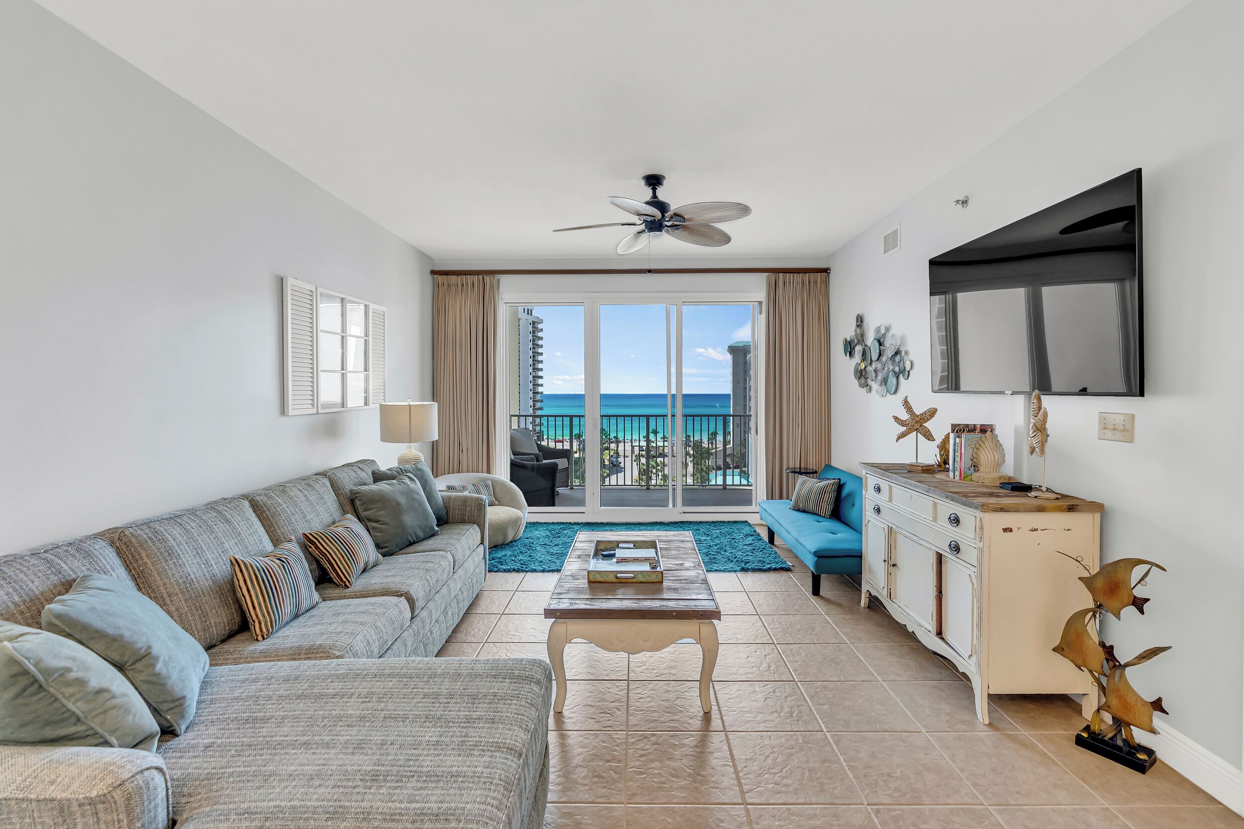 A modern living room with a sofa, coffee table, and a view of the ocean through large windows.