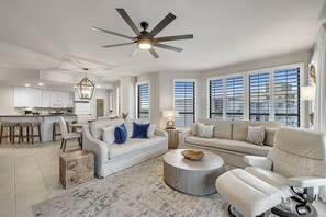 Un salon spacieux avec un grand canapé, une table basse et un ventilateur de plafond.