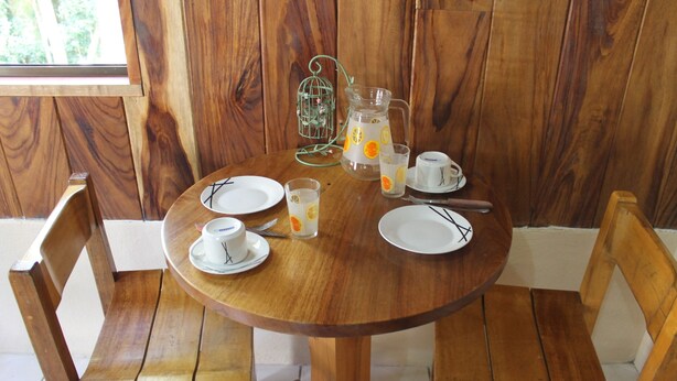 A wooden dining table set with white plates, a pitcher, glasses, and a birdcage decoration. - Monteverde romantic cabaña (Monteverde)