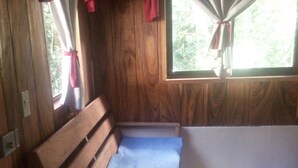 A wooden bench with a blue cushion in a room with wooden walls and a window with red curtains. - Monteverde romantic cabaña (Monteverde)