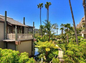 A resort with a pool, palm trees, and a building with a balcony. - Tropical Water View at North Coast Village C200 (Oceanside)