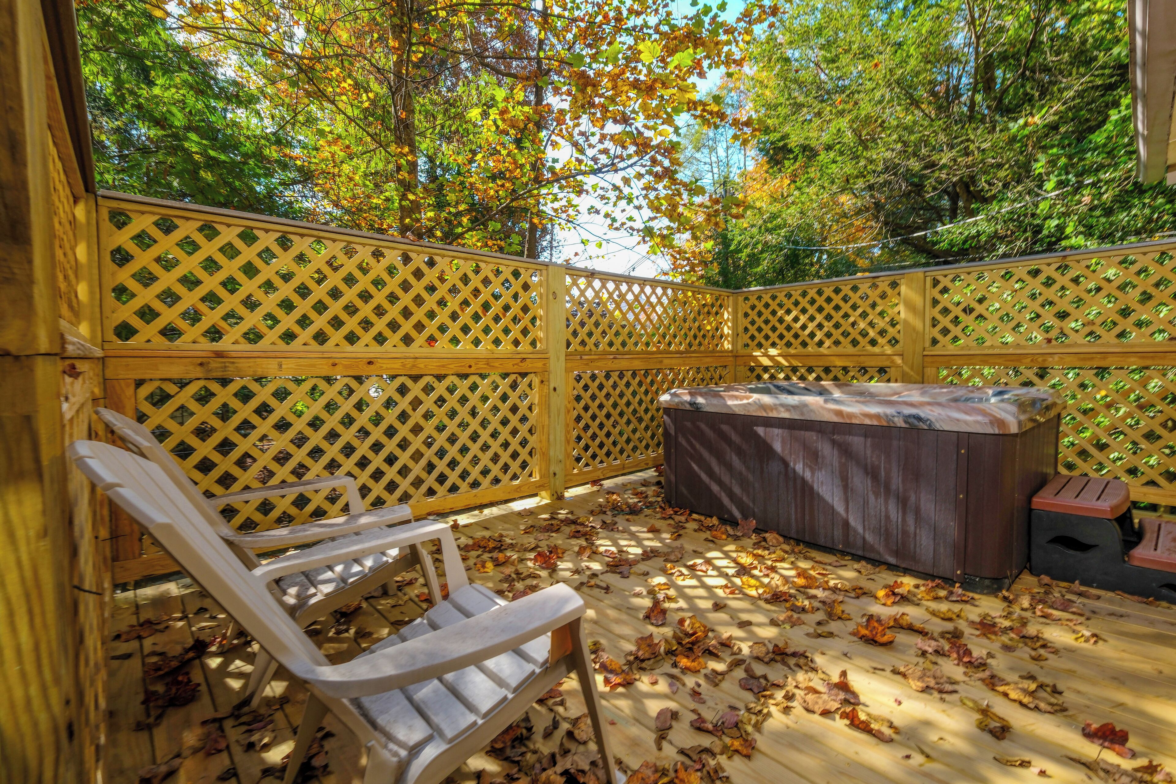 Een houten terras met een jacuzzi, een houten stoel en een latten hek.