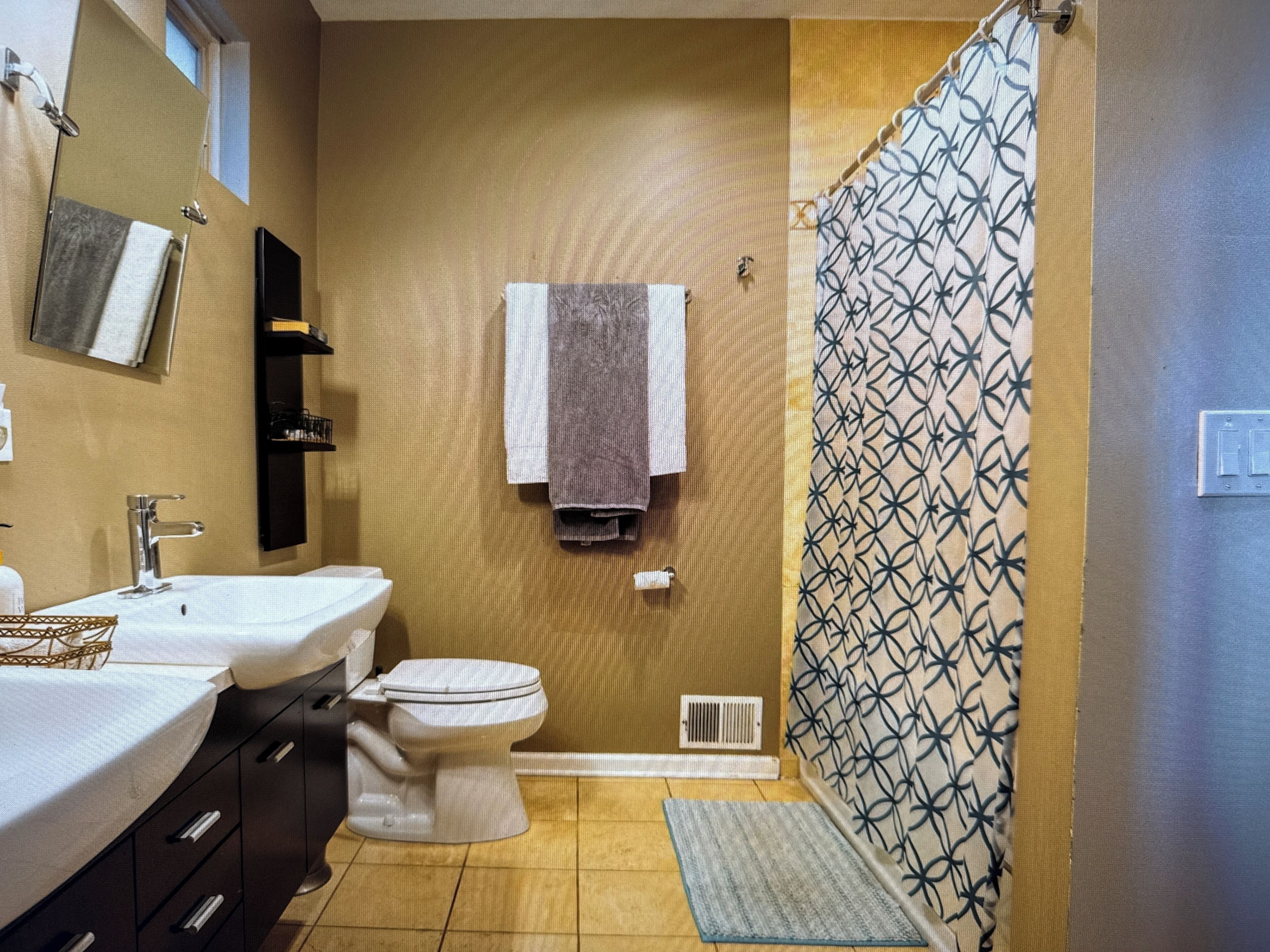 A bathroom with two sinks, a toilet, a shower curtain, and a towel rack.