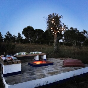 An outdoor seating area with a fire pit, a table, and a bench.