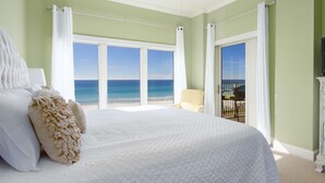 A bedroom with a large bed, white bedding, and a view of the ocean through floor-to-ceiling windows. - BREATHTAKING WATER VIEWS!!! Pools/Hot TubRestaurant/Pickleball/PutPutGolf - Tops'l Beach Manor (Miramar Beach)