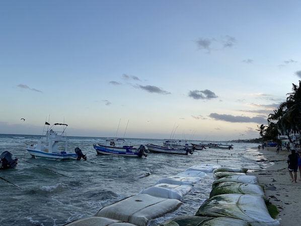 Une plage avec des bateaux amarrés et une rive sablonneuse où se trouvent des gens.