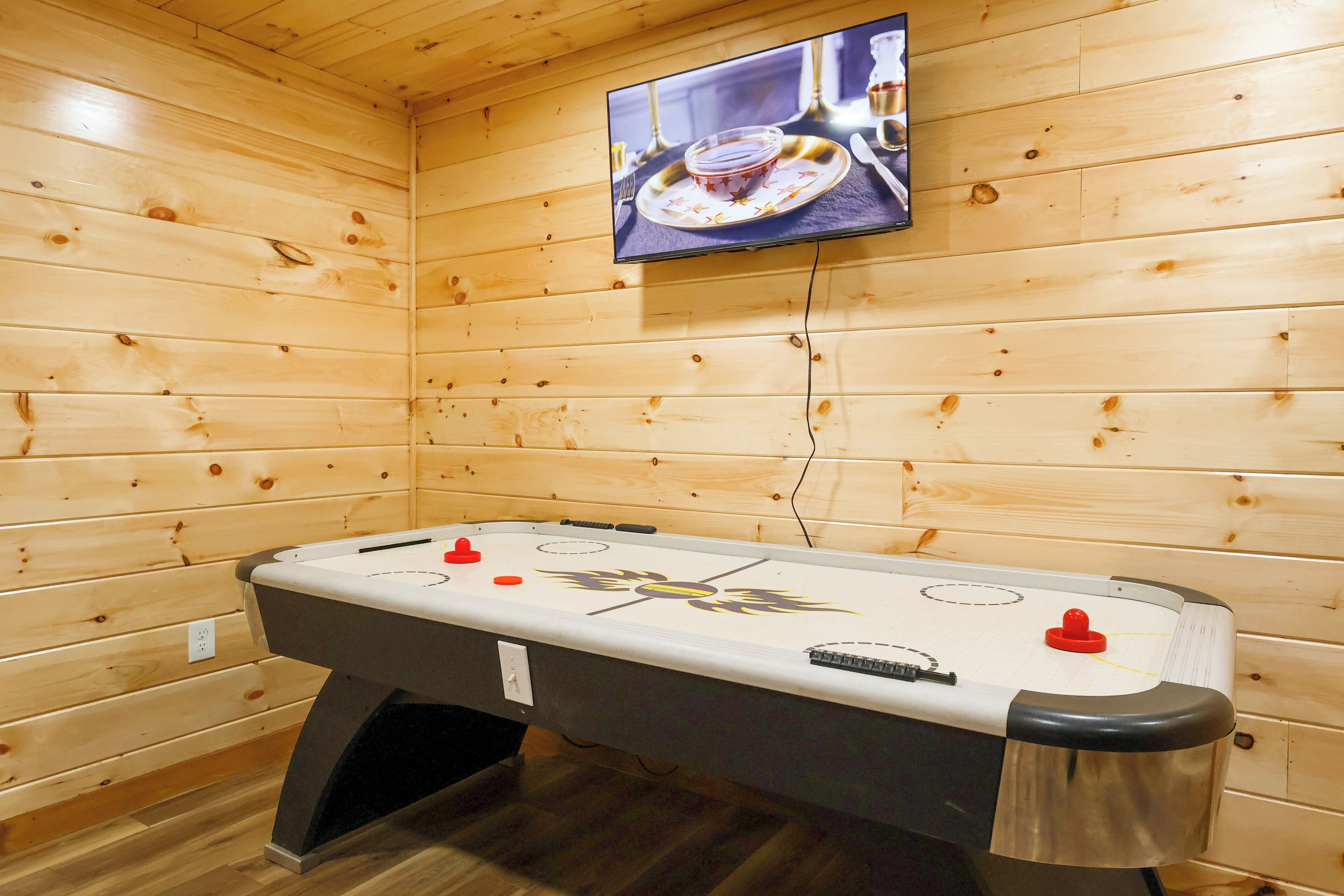 Una habitación con paneles de madera, una mesa de fútbol de mesa y un televisor montado.