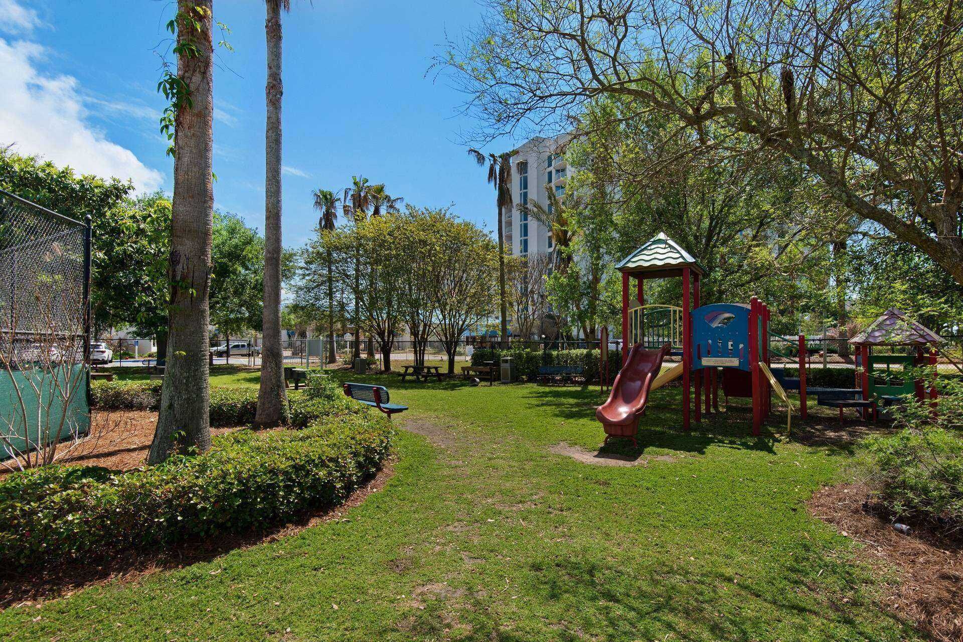 A park with playground equipment, a gazebo, and a building in the background.