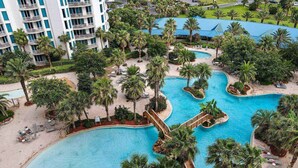 Un complexe hôtelier doté de plusieurs piscines, de palmiers et d’un grand bâtiment avec des balcons.