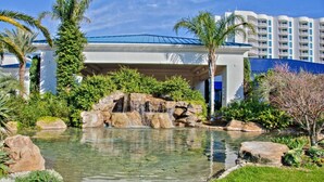 Un hôtel doté d’une piscine, de palmiers et d’une cascade.