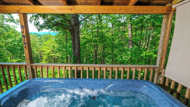 Ein Whirlpool mit Holzterrasse und Blick auf einen Wald.