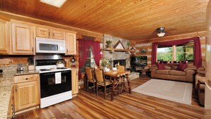 Ein Holzblockhaus-Innenraum mit Küche, Essbereich und Wohnzimmer.