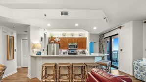 Una cocina moderna con armarios de madera, una isla central con taburetes de bar y vistas a un balcón.