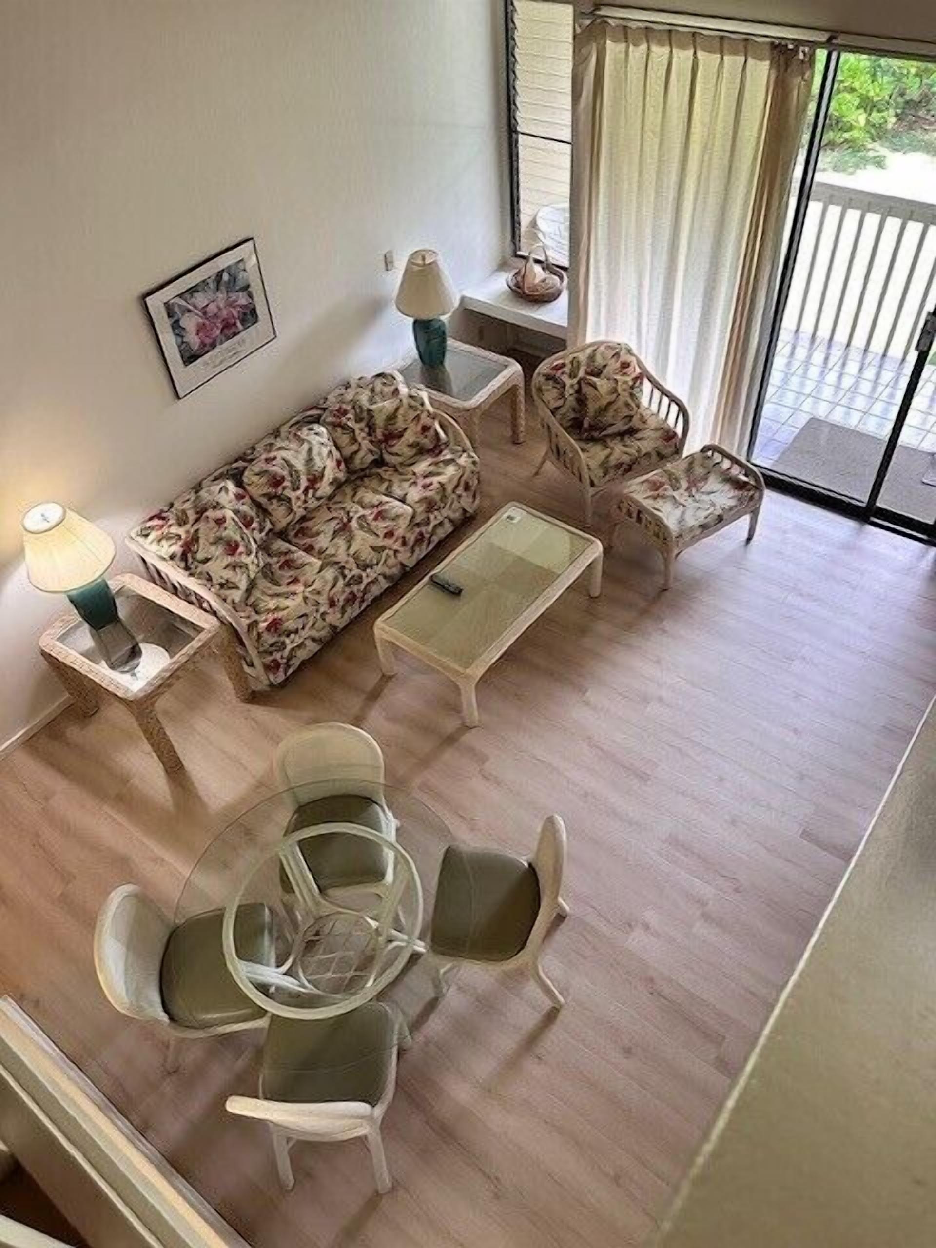 A room with a sofa, two chairs, a small table, a lamp, and a picture on the wall.