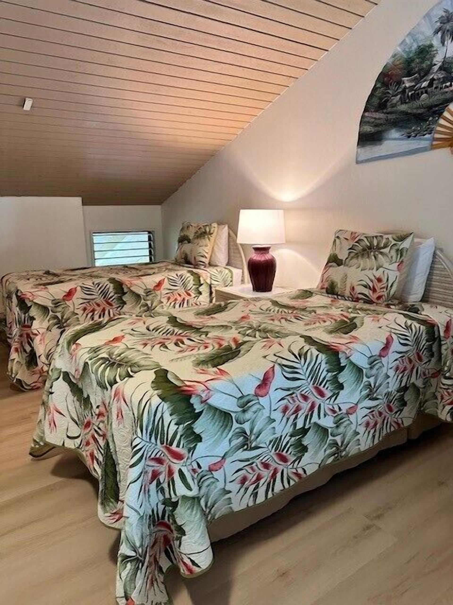 Un dormitorio con dos camas, una mesita de noche, una lámpara y un cuadro en la pared.