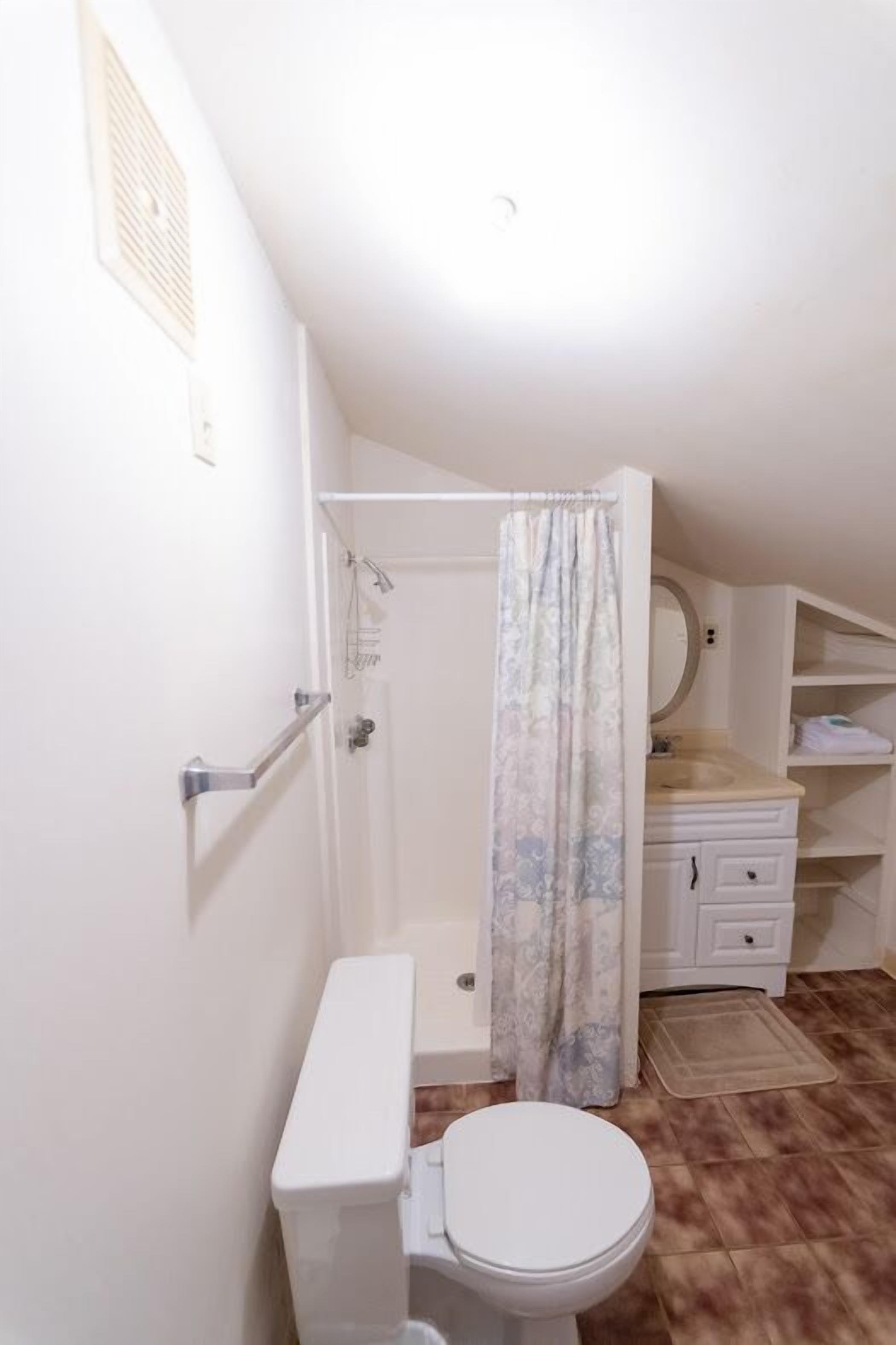 Pieni, käytännöllinen kylpyhuone, jossa on wc, suihku ja pesuallas.
