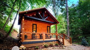 Una cabaña de madera con porche, mobiliario exterior y una escalera que conduce a la entrada.