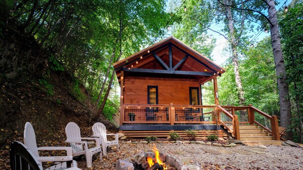 Una cabaña con terraza, fogata y sillas tipo Adirondack.