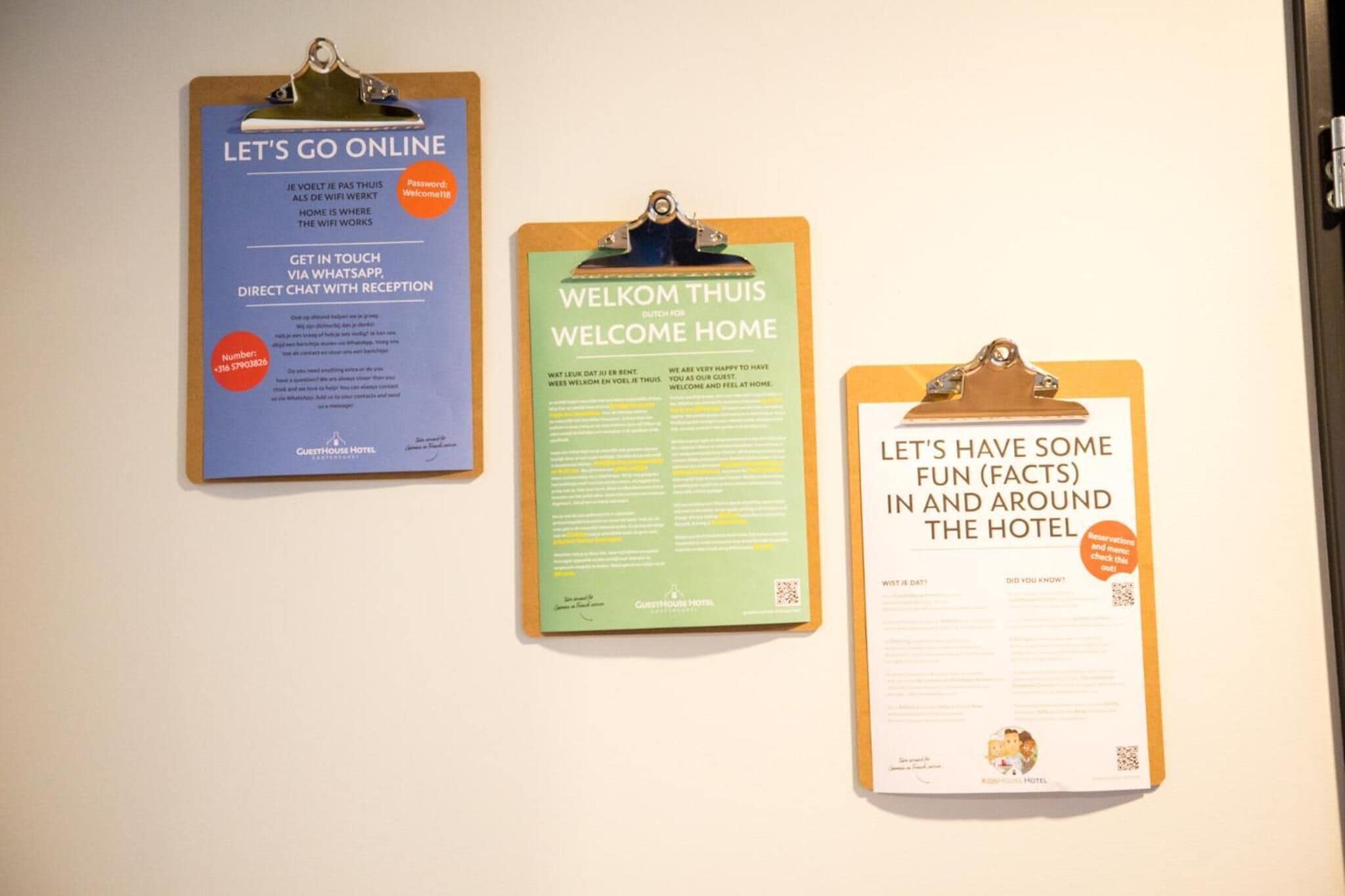 Three informational signs on a wall: 'LET'S GO ONLINE' with WiFi details, 'WELCOME THUIS' with hotel information, and 'LET'S HAVE SOME FUN (FACTS) IN AND AROUND THE HOTEL' with fun facts.