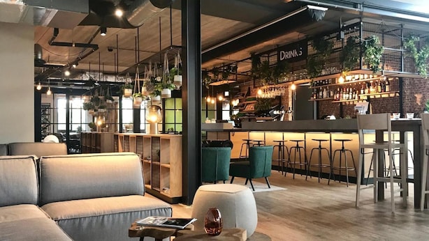 A modern bar area with a counter, bar stools, and a sign that reads "DRINKS". - GuestHouse Hotel Kaatsheuvel (Kaatsheuvel)