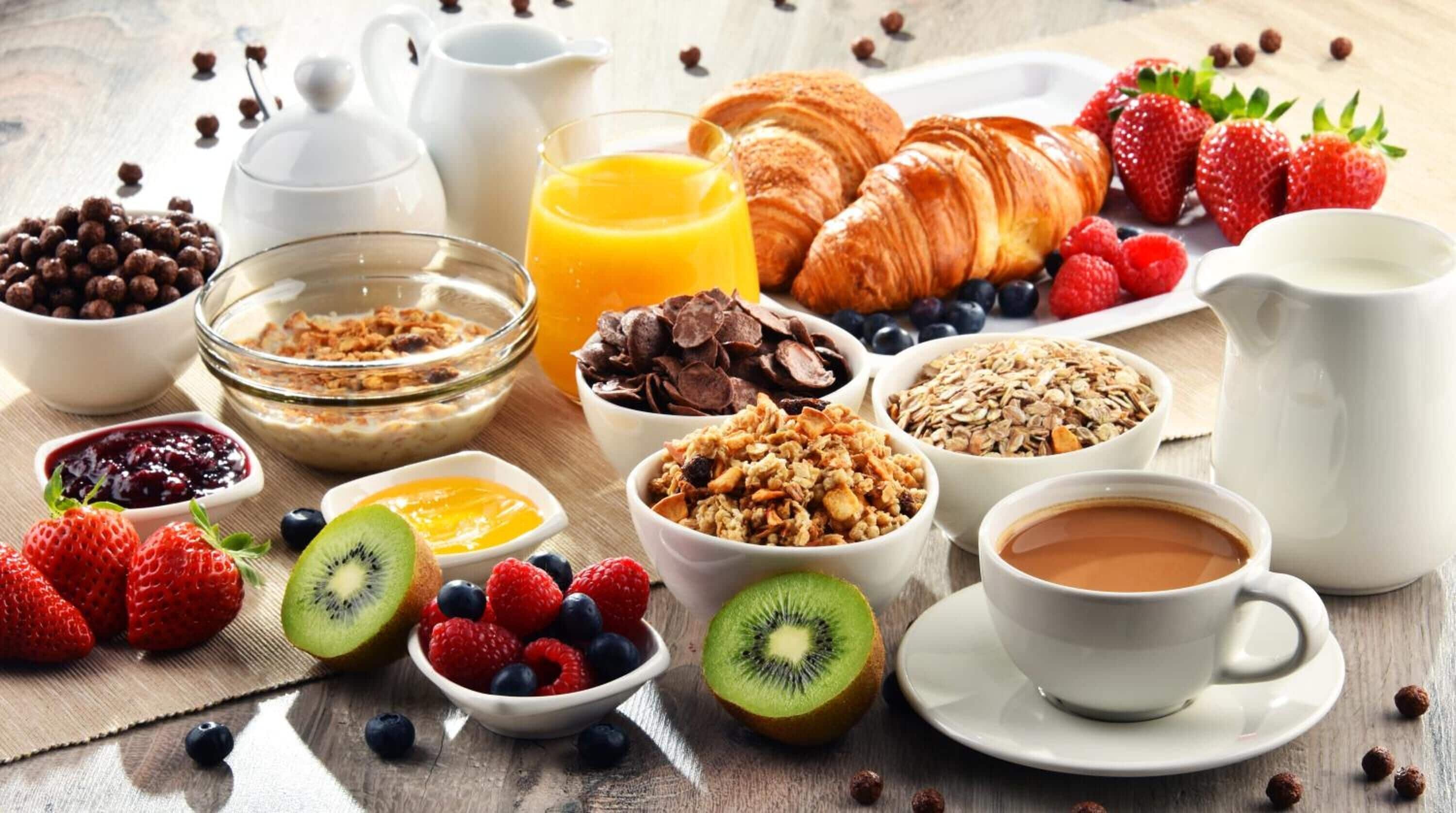 Desayuno con cruasanes, fresas, arándanos, kiwi y diferentes cereales.