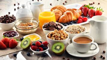Desayuno con cruasanes, fresas, arándanos, kiwi y diferentes cereales.