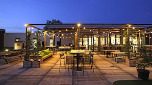 An outdoor patio area with tables and chairs, string lights, and potted plants. - GuestHouse Hotel Kaatsheuvel (Kaatsheuvel)
