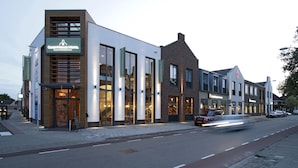 A modern hotel with a prominent sign, large windows, and a brick facade. - GuestHouse Hotel Kaatsheuvel (Kaatsheuvel)