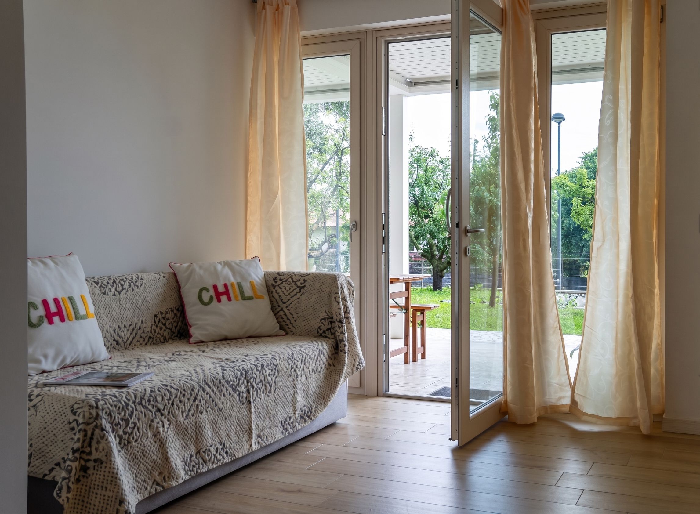 A room with a sofa, a sliding glass door leading to an outdoor area with a table and chairs.