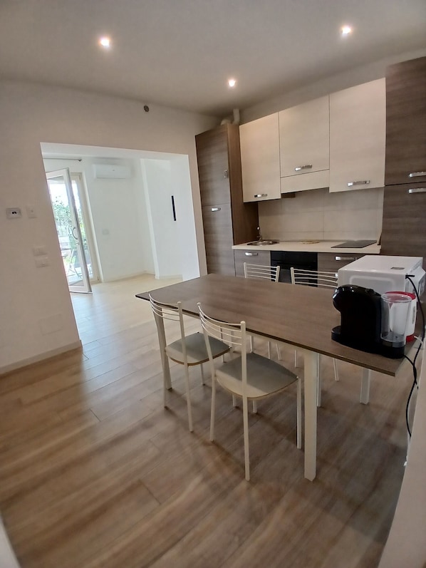A modern kitchen with a wooden table and chairs, a built-in oven, and a coffee maker.