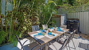 Een terras buiten met een houten tafel voor vier personen, omringd door stoelen.