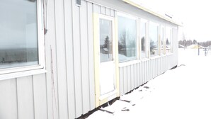 Un bâtiment blanc avec de grandes fenêtres et une porte, entouré de neige.