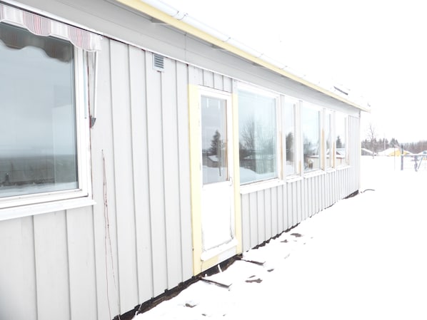 Um edifício branco com janelas amplas e uma porta, rodeado por neve.