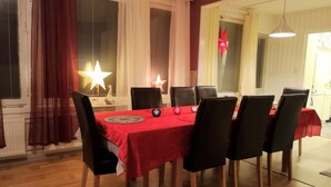 Un coin repas avec une nappe rouge, des chaises noires et une lampe en forme d’étoile.