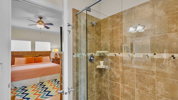 Une chambre d’hôtel avec un lit, une douche et un ventilateur de plafond.
