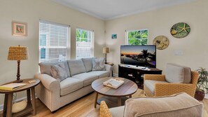 Ein Wohnzimmer mit Sofa, Couchtisch, Fernseher und Dekorationselementen.