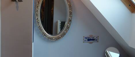A bathroom with a white sink, a large ornate mirror, and a skylight above.