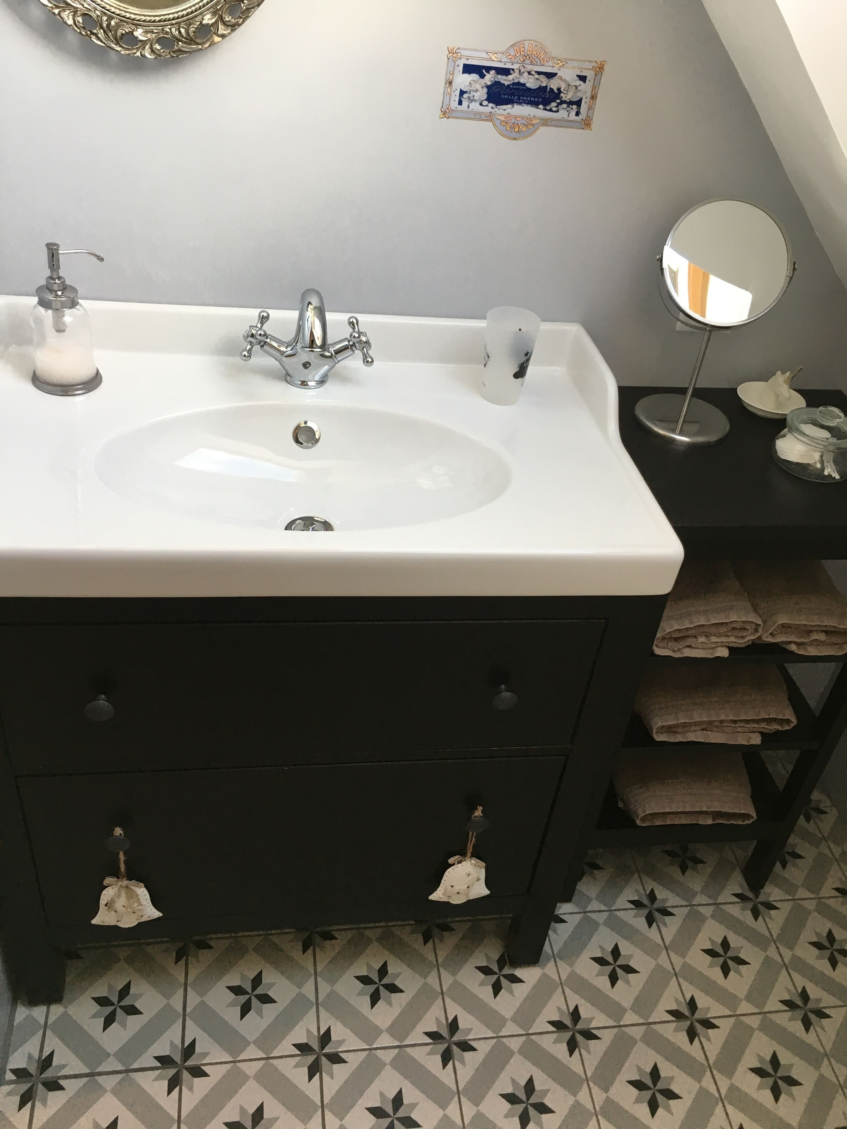 A bathroom with a white sink, black vanity, and a mirror.