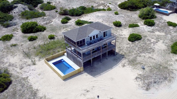 A two-story beachfront house with a pool, surrounded by sand and sparse vegetation. - The Weathervane | 3BR Carova Beach 4x4 OBX | 4 night stay available | Pets (Carova)