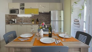 Une cuisine moderne avec une table à manger pour quatre personnes, équipée d’un réfrigérateur, d’un four à micro-ondes et de divers appareils de cuisine.