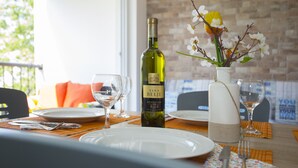 Une table à manger dressée avec des assiettes, des couverts et une bouteille de vin Vina Belje.
