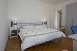 A bedroom with a bed, bedside tables, a chair, and a wardrobe.