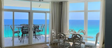 A room with a balcony, a ceiling fan, and a table with chairs.