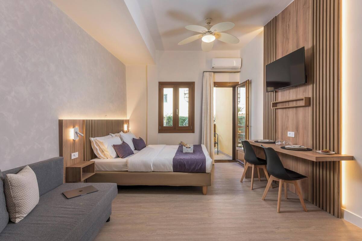 A modern bedroom with a bed, a desk, and a TV.