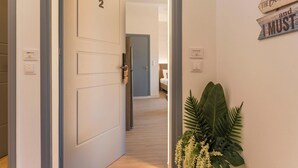 A hallway with a door labeled '2' leading to a bedroom. There is a sign on the wall that reads 'Booty in a Beach is and I must.' - Porto Orion Studios (Chania)