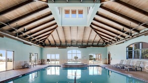 Une grande piscine intérieure dotée d’un haut plafond et éclairée par la lumière naturelle qui entre par de grandes fenêtres.